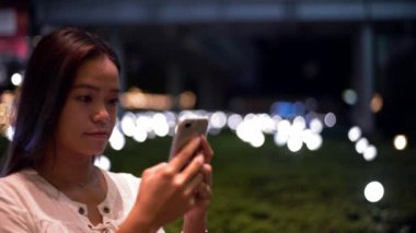 4K, kadın el ele tutuşmasını kapat ve arka plandaki ışıkla ekrandaki akıllı telefona dokun. Taipei 'de cep telefonu kullanan Asyalı bir kadın. Akıllı telefondan kız mesajlaşması. Cihaz mobil Dan kullanan insanlar