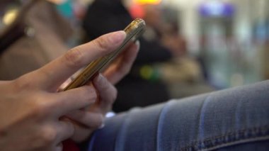 4K Genç, Asyalı güzel bir kadın Tayvan havaalanında cep telefonuyla yazı yazıyor. Çekici kız akıllı telefonu kontrol et. Bekleme odasında oturan insanlar seyahat etmek için uçağa biniyorlar.