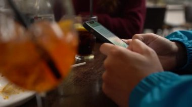 4K, beyaz adam barda akıllı telefon kullanıyor, bir bardak aperol kokteyli. İtalyan restoranında cep telefonuna dokun. İnternette sörf yapmak, sosyal ağı kontrol etmek ve mobil Dan 'e metin yazmak