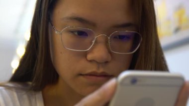 4K Asyalı Kadın Tayvan 'daki bir kahve dükkanında akıllı telefon kullanarak insanlarla sohbet ediyor ve iletişim kuruyor. İnternette sörf yapmak için iyi bir zaman, sosyal ağları kontrol etmek ve onun telefon cihazına yapılan metinleri yazmak için.