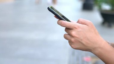 4K, Sevilla caddesinde tutulan ve daktilo kullanan Asyalı turist kadını kapat. Kız, İspanya 'da akıllı telefonları ve internette sörf yapmayı kontrol ediyor. Seyahat sırasında cihaz telefonu kullanan gezgin