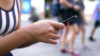 4K, Sevilla caddesinde tutulan ve daktilo kullanan Asyalı turist kadını kapat. Kız, İspanya 'da akıllı telefonları ve internette sörf yapmayı kontrol ediyor. Seyahat sırasında cihaz telefonu kullanan gezgin