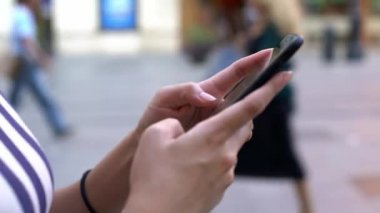 4K, Sevilla caddesinde yürürken cep telefonu tutan ve daktilo kullanan Asyalı turist kadın. İspanya tatilinde akıllı telefonları kontrol edip internette sörf yapmakla meşgul. Gezgin aygıt telefonu kullanıyor - Dan
