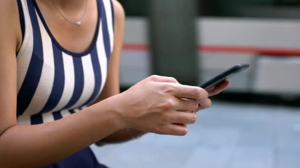 女性手持和触摸屏幕智能手机的闭锁 而电动车背景通过 在塞维利亚街用手机的亚洲女人西班牙的女孩用智能手机发短信 — 图库视频影像