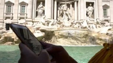 4K, kadın el ele tutuşmasını kapat ve Trevi Fountain ile ekrandaki akıllı telefona dokun. Cep telefonu kullanan Asyalı bir kadın. Akıllı telefondan kız mesajlaşması. Gezginler mobil cihaz kullanıyor