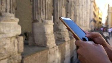 4K, Roma 'daki Piazza di Pietra Meydanı' ndaki Hadrian Tapınağı 'nda cep telefonu tutan ve daktilo eden turist kadını kapatın. İtalya-Dan 'de akıllı telefonları ve internette sörf yapmayı kontrol et.