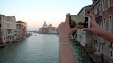 4K, Venedik Bazilikası Santa Maria della Salute 'un fotoğrafını çekmek için akıllı telefon kullanan bir turist kadını çek. İtalya-Dan 'de kameralı telefonla fotoğraf çeken insanlar