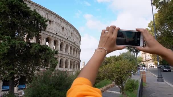 ローマ イタリア 2018年9月24日 4K街の有名なランドマークである美しいコロシアムの写真を撮るためにスマートフォンを使用して観光客の女性を閉じます 休暇でカメラの携帯電話で写真を撮る人々 — ストック動画