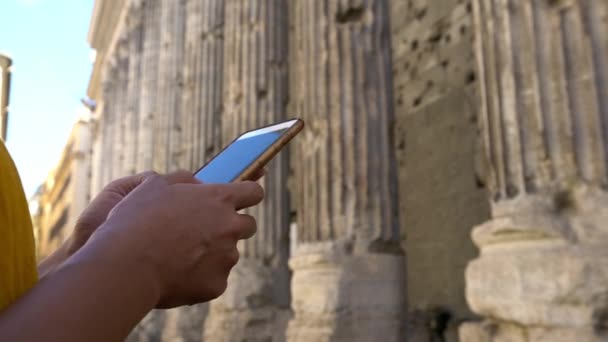 アジアの女性は ピアッツァ ピエトラのハドリアヌス神殿の列とスマートフォン上でメッセージ ローマの街で携帯電話の会話をしている女の子 デバイス電話 ダンを利用する旅行者 — ストック動画