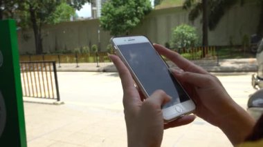 Kuala Lumpur caddesinde cep telefonu kullanan 4K Asyalı kadın. Malezya 'da akıllı telefon kullanan bir kız. Cihaz telefonu kullanan bir turist. İnsanlar akıllı telefonları kontrol eder.
