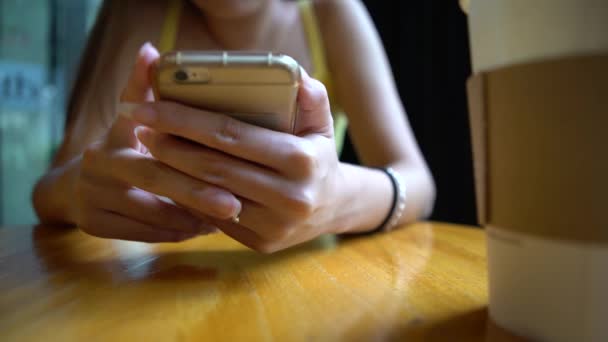4K亚洲女人在咖啡店用智能手机 放松和享受咖啡的好时机 查看社交网络聊天 用她的手机与人联系 — 图库视频影像
