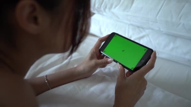 Aziatische Vrouw Tonen Een Groene Scherm Telefoon Met Een Bed — Stockvideo