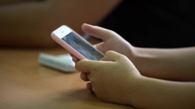 4K kapanış genç öğrencileri telefonda bir mesaj okuyorlar. Sınıftaki ahşap bir masanın üstünde akıllı telefon ekranı gören çocuklar. Bilgi aramak için akıllı telefonu tutan bir genç. Eğitim kavramı. - Dan.