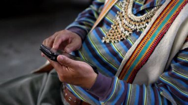 4K, akıllı telefon kullanarak yerli elini kapat ve kabilenin geleneksel kıyafetlerini giydir. Tayvanlı yerli bir adam Formosan köyündeki bir telefon cihazına bakıyor.