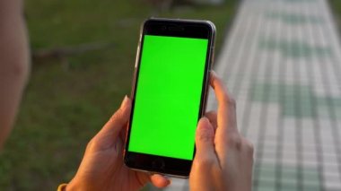 4K Asyalı kadın parkta yürüyüş yapıyor ve Taipei 'de sahte yeşil ekran akıllı telefon gösteriyor. Reklam için telefon kullanılıyor. Tayvan 'ın güzel bahçesi Dan' de cep telefonu tutan kadın eller.