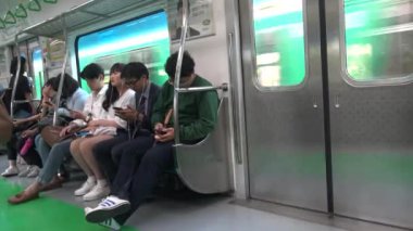 Seul, Güney Kore-12 Eylül 2015: 4K Asyalı genç kadın trende oturuyor telefonunu kontrol ediyor, sosyal ağda yayınlanması için resimli telefona bakıyor, Kore-Dan durağına varmasını bekliyor.
