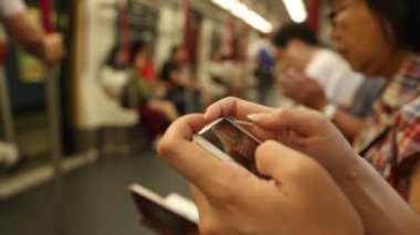 Kowloon, Hong Kong-19 Haziran 2016: Hong Kong metrosunda akıllı telefon kullanan Asyalı kadın, oturun ve metroda telefon çalın.