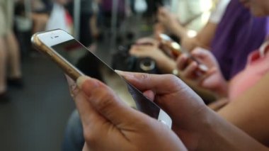 Trende bekleyen kadın, telefon cihazını tamir etmek için iyi bir zaman. Akıllı telefonu kullanarak e-postalarını ve yazışmalarını kontrol etmek için. Hong Kong-Dan 'deki durak istasyonuna varmayı beklerken.