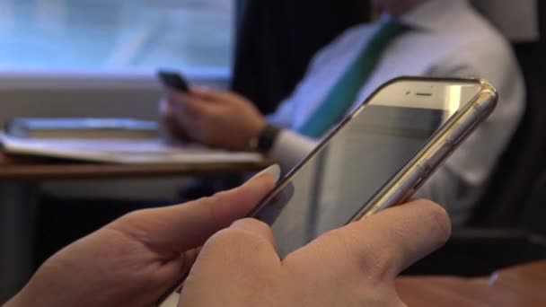 4K Asian Hand Woman à l'aide d'un téléphone portable à écran tactile à l'intérieur Train avec homme d'affaires s'asseoir Arrière-plan. Fille tenant Smartphone, Voyage pour faire le travail. Surfer sur Internet et vérifier les réseaux sociaux-Dan 