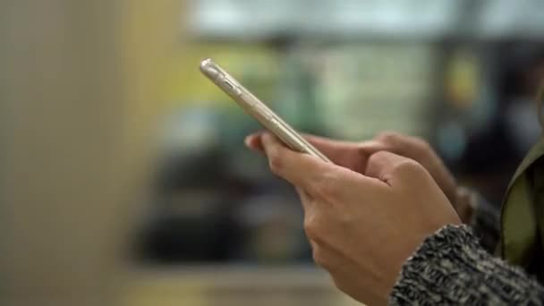 4K, Jeune femme asiatique utilisant un smartphone sur la plate-forme active du métro. Comme un train passe, fille vérifie les réseaux sociaux et écrire du texte fait sur l'appareil téléphonique, quai de la gare d'Osaka. Japon-Dan 