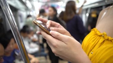 Metroda akıllı telefon kullanan 4K Genç Asyalı kadın. Kız sosyal ağları kontrol ediyor ve Tokyo tren istasyonu Japonya-Dan 'e ait telefon cihazına mesaj yazıyor.