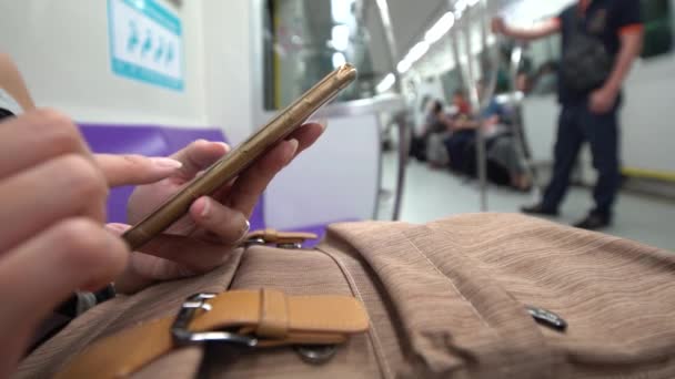 地下鉄で4Kアジアの若い女性が携帯電話をチェックし Line ソーシャルネットワークを使用して友人とSmsテキストを書きます — ストック動画