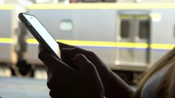 アクティブな地下鉄のプラットフォームで女性の手のホールドとタッチスクリーンスマートフォンの閉鎖 携帯電話を使用して忙しいアジアの女性 電車の駅での旅行中にスマートフォンで女の子のメッセージング — ストック動画
