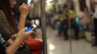 4K Asyalı insanlar trende oturup Smartphone kullanarak aynı oyunu oynarlar ve sohbet etmek ve iletişim kurmak için sosyal ağı kontrol ederler. Tayvan-Dan metrosundaki telefon cihazına bakıyorum.