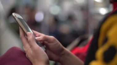 4K Asyalı genç kadın bir trende oturup telefonuna bakıyor ve arkadaşlarıyla mesajlaşırken hat, sosyal ağ kullanarak Tayvan-Dan durağında durmasını bekliyor.