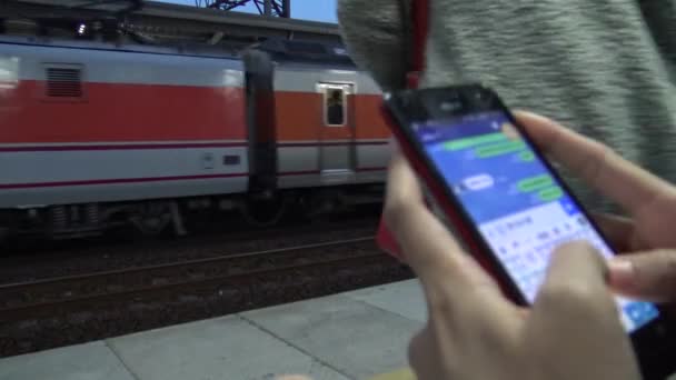 4Kは アクティブ地下鉄プラットフォーム上でスマートフォンを使用して超 若いアジアの女性を持っていました 電車が通過すると 女性はソーシャルネットワークをチェックし 彼女の携帯電話のデバイス上で行わテキストを書き込み 台湾駅のプラットフォーム — ストック動画