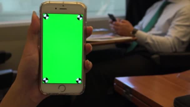 4K亚洲手妇女展示绿色屏幕手机内的火车与商人坐下来背景 拿着智能手机的女孩 用在一个广告上 — 图库视频影像