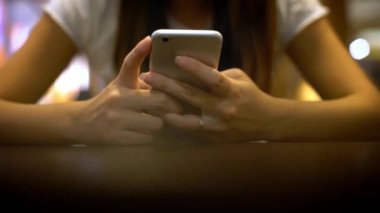 Restoranda oturan, konuşan ve wirth cep telefonuna mesaj atan 4K Genç Asyalı kadın. Tayvan 'ın kafeteryasında yemek ve içecek beklerken Smartphone' u sosyal ağları, e-postaları ve resimleri görmek için kullanıyor.