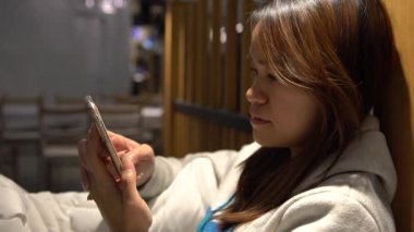 4K Güzel Asyalı Kadın Restoranda Beklerken, telefon cihazında bazı işleri halletmek için iyi bir zaman, akıllı telefonu e-posta ve yazışma metinlerini kontrol etmek için kullanarak, bekliyor.