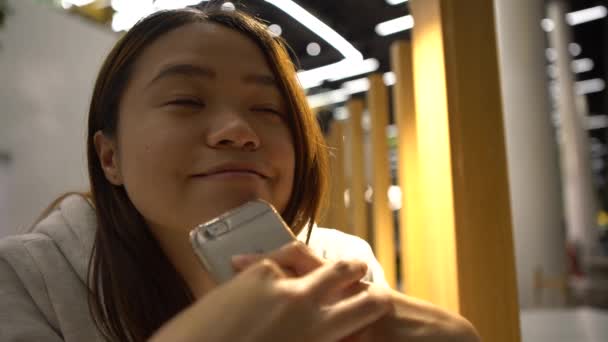 4K微笑快乐美丽的亚洲女人在餐馆等候是一个很好的时机 可以在你的手机上完成一些工作 用智能手机来欺骗她的电子邮件和写短信 就像她等待丹一样 — 图库视频影像