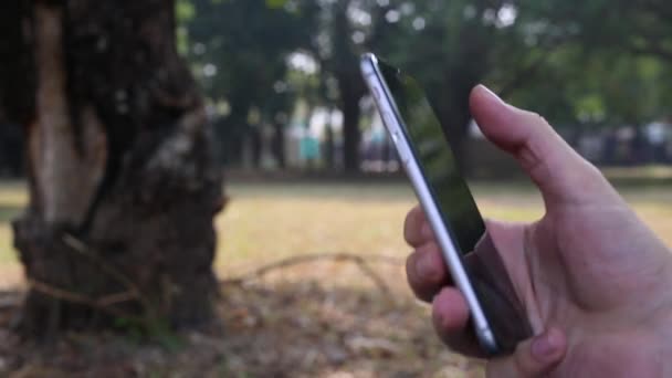 Человек Использующий Смартфон Парке Хорошее Время Увидеть Свою Социальную Сеть — стоковое видео