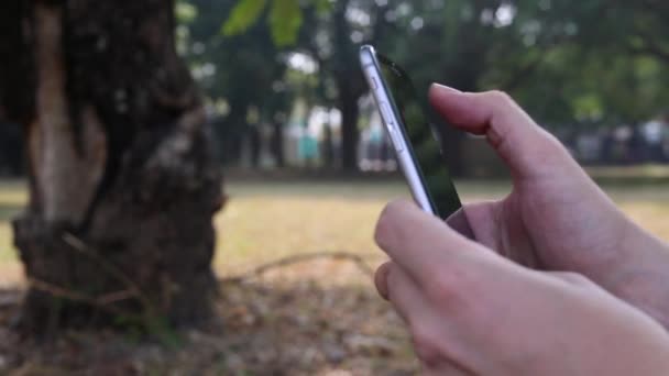 Man Met Behulp Van Smart Phone Een Park Een Goed — Stockvideo