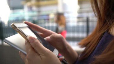 4K Asyalı genç kadın Hong Kong caddesinde akıllı telefon kullanarak kısa mesajlar atıyor. Telefonunu kontrol ediyor ve arkadaşlarıyla SMS metni yazıyor. Hat, sosyal ağ Dan kullanıyor.