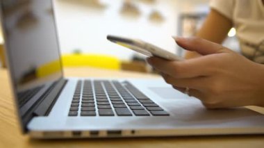 4K Close Up of Asian Business kadını cep telefonu kullanıyor ve laptopunu kahve makinesinde çalışmak için kullanıyor.