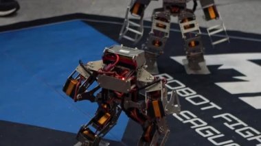 Yarışma robotu teknolojisinin Yavaş Hareketi. Bir çift modern robot kavga ediyor. Akıllı robot dövüşü. Öğrenciler yerde kontrol robotu kullandılar. Mühendislik, teknoloji kampı eğitimi.