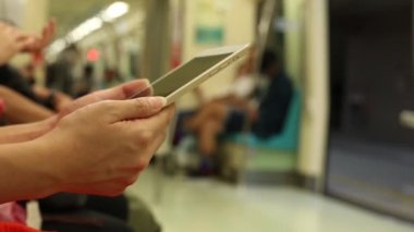 Asyalı genç bir kadın bir trende oturur tablet bilgisayarını kontrol eder, sosyal ağı görür, Tayvan-Dan durağına varmasını bekler.