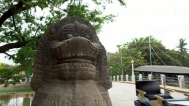 Siem Reap, Kamboçya-17 Nisan 2018: 4K, Sokaktaki Aslan heykeli Arabalar ve yol kenarında tuk tuk. Kamboçyalılar yolda scooter ve motosiklet sürüyorlar. Şehir merkezinde sahne - Dan