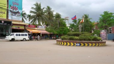 Siem Reap, Kamboçya-17 Nisan 2018: 4K, Roundabout on the road. Yol kenarındaki bir heykel etrafında trafik vardı. Kamboçyalılar eski kasaba sokaklarında scooter ve motosiklet kullanıyor.