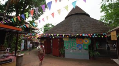 Siem Reap, Kamboçya-17 Nisan 2018: 4K, Asyalı kadın turist Siem Reap binalarının etrafında ahşap çatısı ve Kamboçya 'daki yerel festivalde birçok rengin flaması ile yürüyor. Asyalı kent- Dan