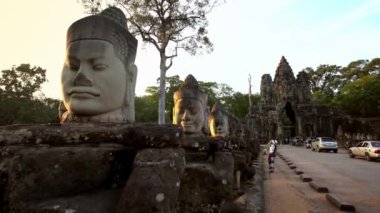 Siem Reap, Kamboçya-18 Nisan 2018: 4K, Turist kadın Angkor Wat Kuzey Kapısı önünde dev gardiyanların akıllı telefonuyla fotoğraf çekiyor. Kamboçya tapınak kompleksinin ünlü simgesi. Khmer kültürü - Dan