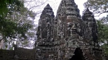 4K, Siem Reap 'teki Angkor Thom Tapınağı' nın güzel kuzey kapısından yüz detayları. Büyük Khmer heykeli girişi süslüyor, Khmer imparatorluğunun eski başkenti. Kamboçya Ormanı - Dan