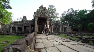 4K, güzel Asyalı kadın Preah Khan 'ın antik Hindu tapınağında yürüyüşe çıktı. Turist kız Kamboçya 'daki arkeolojik tapınakların duvarlarından tek başına geçiyor. Angkor Thom popüler bir cazibe.