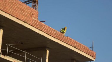 Seville, İspanya-03 Ocak 2019: 4k, tuğla ustası beton ustası katman bina işçisi. Güneşli bir günde inşaat halinde olan yeni bir bina. Çamur tuğlaları çimento harcı ile bağlanır.