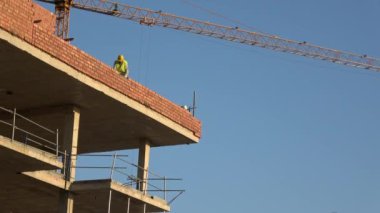 Seville, İspanya-03 Ocak 2019: 4k, tuğla ustası beton ustası katman bina işçisi. Güneşli bir günde inşaat halinde olan yeni bir bina. Çamur tuğlaları çimento harcı ile bağlanır.