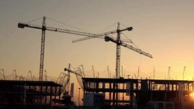 Seville, İspanya-03 Ocak 2019: 4K, inşaat ve sanayi kulesi vinçleri olan gün batımı. Şafak sökücü vinç şehirde bir evde çalışıyor. Sarı güneş ışığı olan yeni bina Dan.