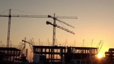 Seville, İspanya-03 Ocak 2019: 4K, inşaat ve sanayi kulesi vinçleri olan gün batımı. Şafak sökücü vinç şehirde bir evde çalışıyor. Sarı güneş ışığı olan yeni bina Dan.